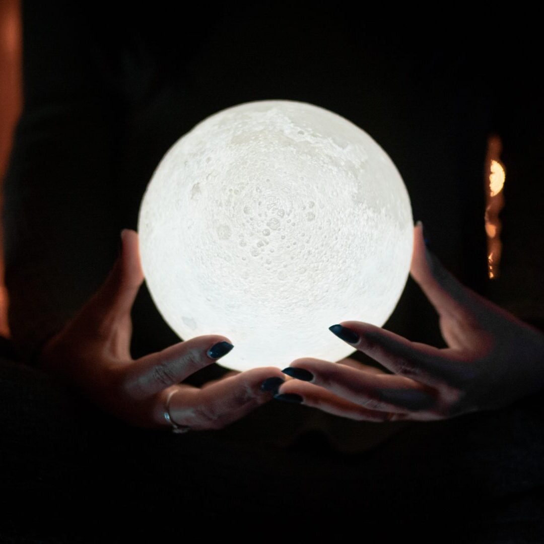 A person holding their hands over the moon.